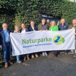 Geschäftsführende der Naturparke halten Banner von Naturparke 24 hoch